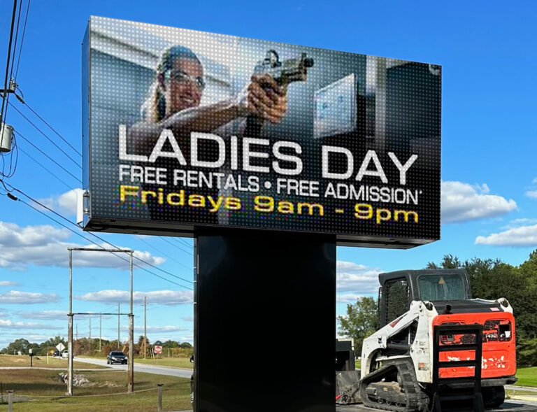 A digital sign advertises Ladies Day with free rentals and admission, Fridays 9am-9pm, at a shooting range.